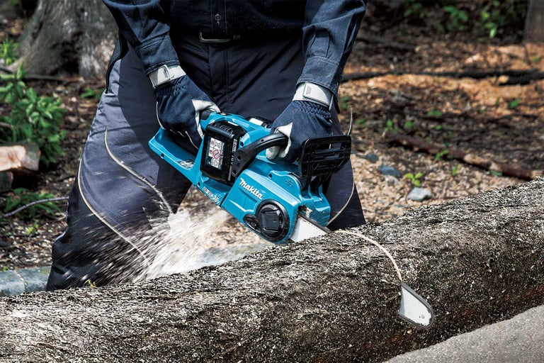Person sägt Baumstamm mit Akku-Kettensäge von Makita