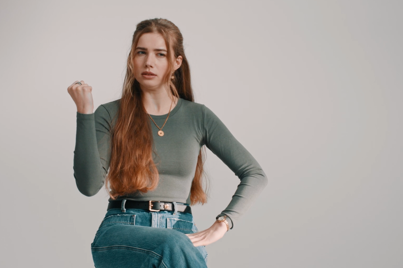 Frau mit Jeans, Gürtel, Langarmshirt und Halskette
