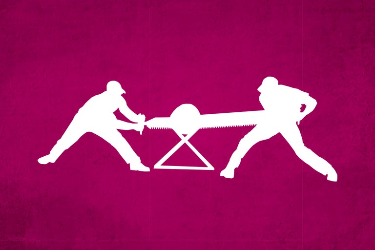 Silhouette von zwei Personen, die gemeinsam mit einer Schrotsäge einen Baumstamm auf einem Sägebock sägen.