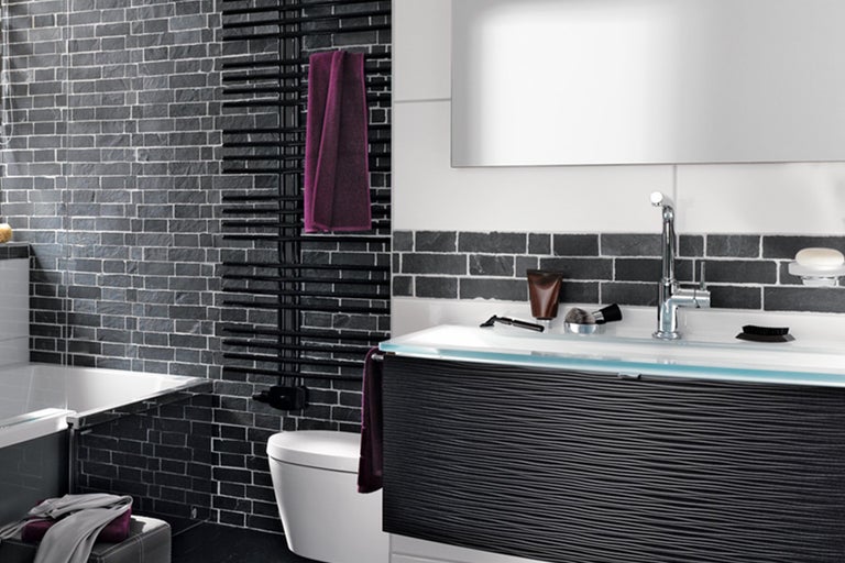 Badezimmer mit Waschtisch, Spiegel, Handtuchwärmer und Fliesenwand