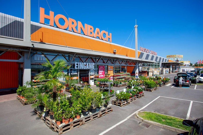 Außenansicht eines Hornbach Baumarktes mit Pflanzen und Produkten vor dem Eingang