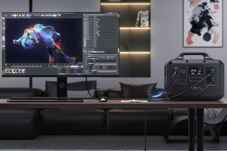 Stromgenerator mit Display neben einem Computermonitor auf einem Tisch.