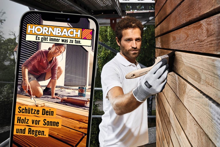 Ein Mann streicht eine Holzfassade, während auf einem Smartphone eine Frau beim Ölen einer Holzterrasse mit Hornbach Logo und Slogan zu sehen ist.