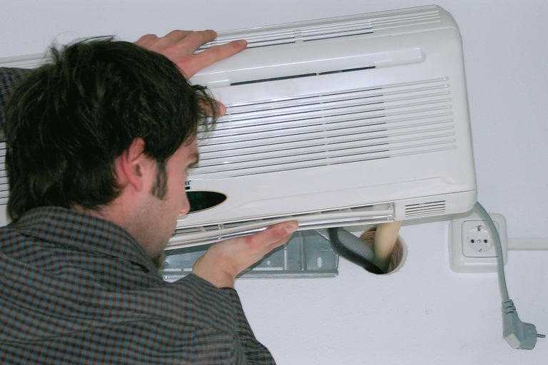 Ein Mann installiert eine Klimaanlage an einer Wand.