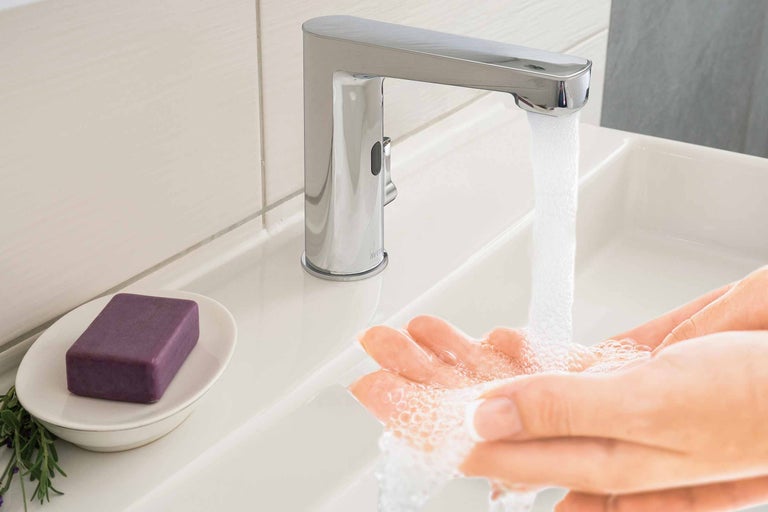 Händewaschen unter einer Armatur mit Sensor im Badezimmer