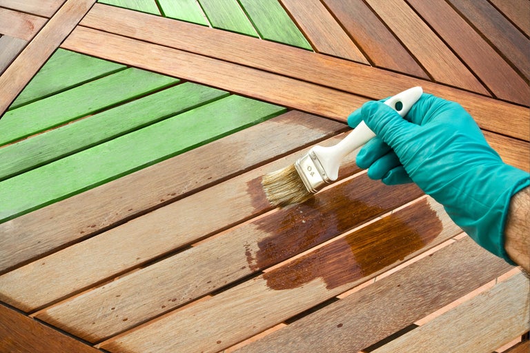 Holzterrasse wird mit einem Pinsel bearbeitet
