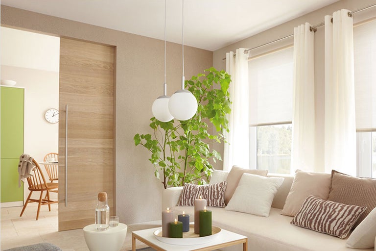 Wohnzimmer mit Couch, Kissen, Vorhängen, Lampe und Schiebetür