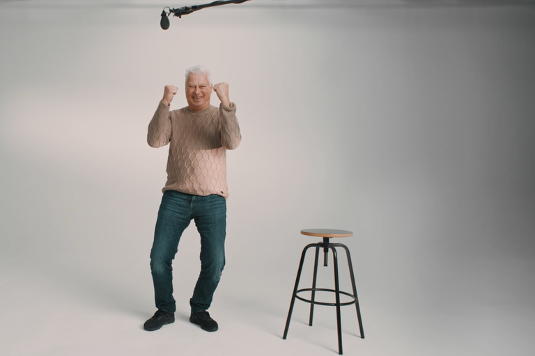 Mann mit erhobenen Fäusten neben einem Barhocker