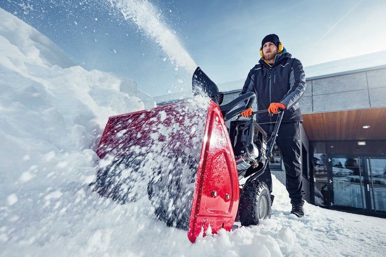 Mann mit Schneefräse räumt Schnee