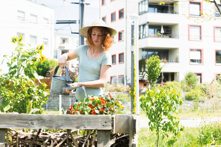 Frau gießt Blumen mit einer Metallgießkanne im Garten