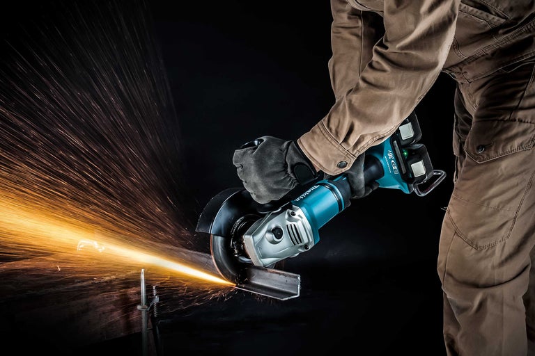 Eine Person arbeitet mit einem Akku-Winkelschleifer der Marke Makita an einem Werkstück, wobei Funken entstehen.