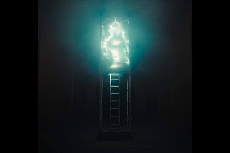 Leiter vor einem beleuchteten, wabenförmigen Objekt