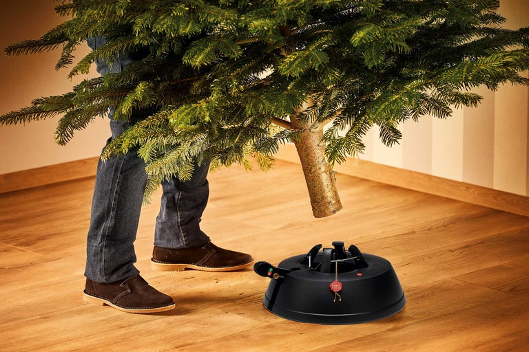 Person setzt einen Weihnachtsbaum in einen Christbaumständer