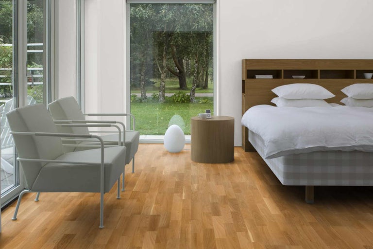 Heller Schlafraum mit Holzboden, Sesseln und Bett