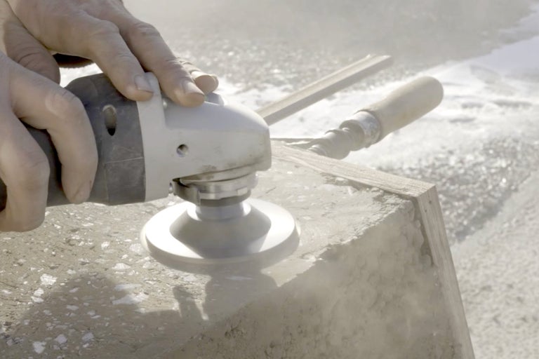 Ein Mann schleift Beton mit einer Betonschleifmaschine.