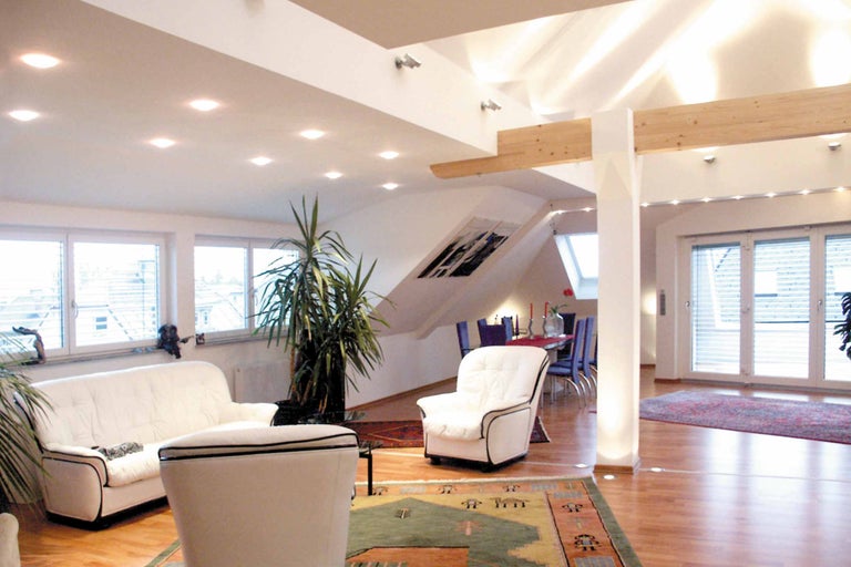 Helles Wohnzimmer mit Sofa, Sessel, Esstisch und Zimmerpflanze