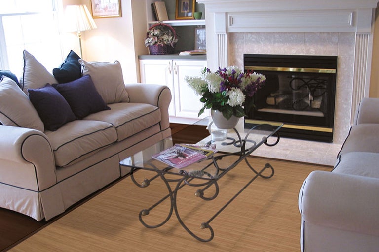 Wohnzimmer mit Sofa, Couchtisch mit Glasplatte und Kamin.