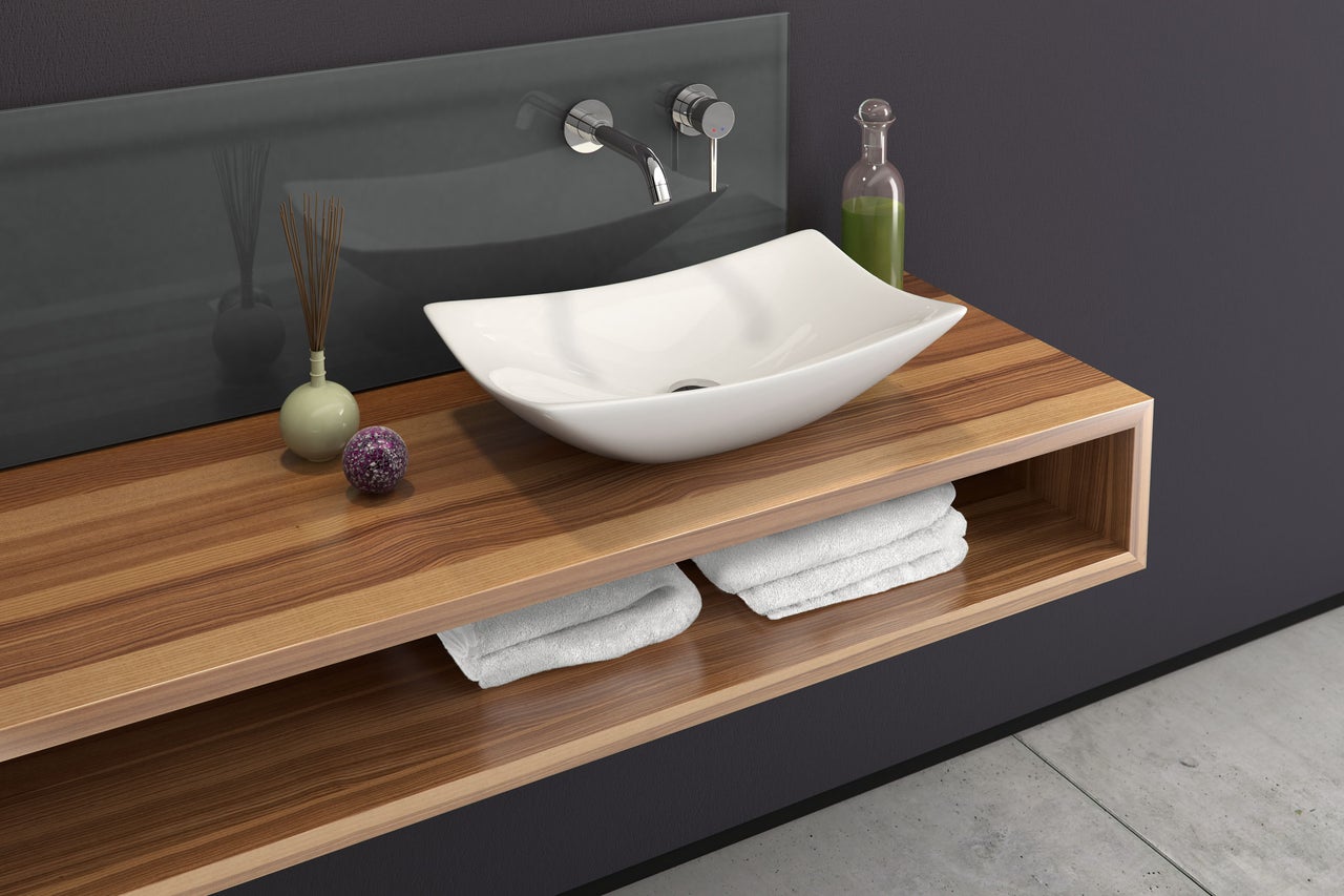 Modernes Badezimmer mit Aufsatzwaschbecken, Holztisch und Handtüchern.