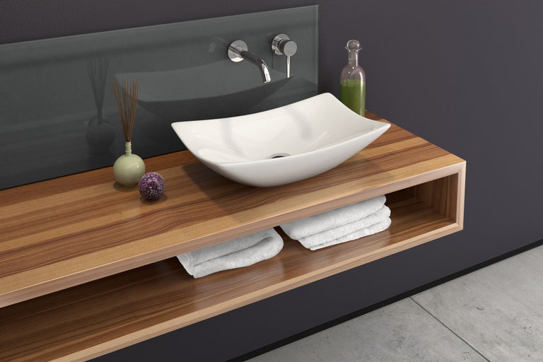 Modernes Badezimmer mit Aufsatzwaschbecken, Holztisch und Handtüchern.