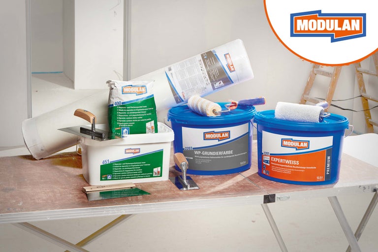 Set mit Modulan Renovierungsprodukten inklusive Wandfarbe, Grundierung, Spachtelmasse, Malervlies und Glättekellen für Malerarbeiten.