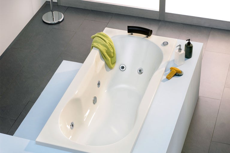Eingebaute Badewanne im Badezimmer mit Handtuch, Seife und Bürste