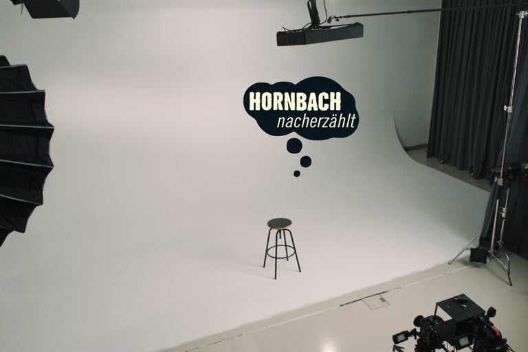 Hornbach Nacherzählt Logo vor neutralem Hintergrund mit Hocker