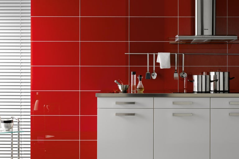 Helle Küche mit roten Fliesen, weißen Unterschränken und Edelstahl-Arbeitsplatte