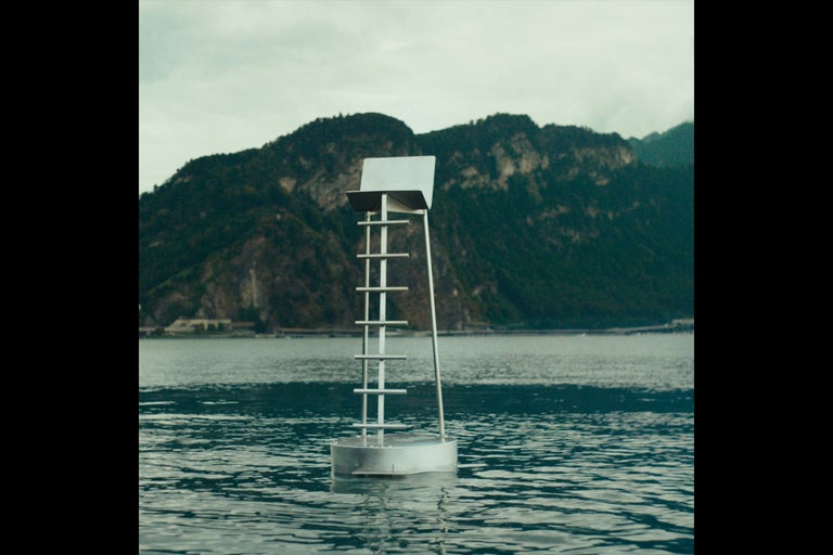 Eine Navigationsbake auf einem See mit Bergen im Hintergrund.