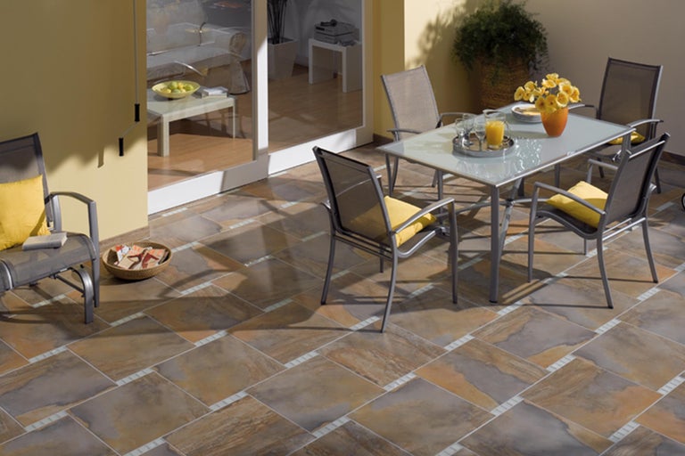 Terrasse mit Tisch, Stühlen und Bodenfliesen in warmen Farben