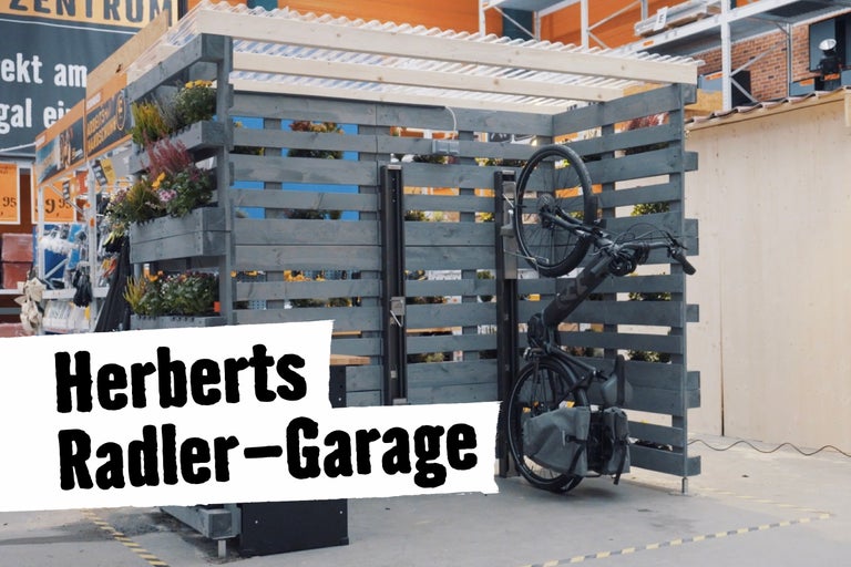 Fahrradgarage aus Holz mit Bepflanzung und aufgehängtem Fahrrad