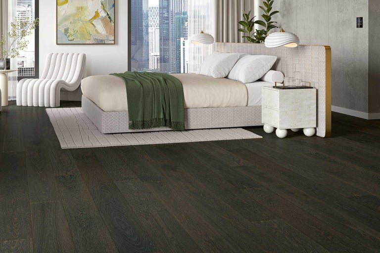 Schlafzimmer mit dunklem Holzboden, Bett und Sessel