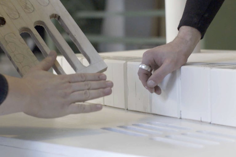 Handwerker arbeitet mit einer Schablone auf einer weißen Oberfläche