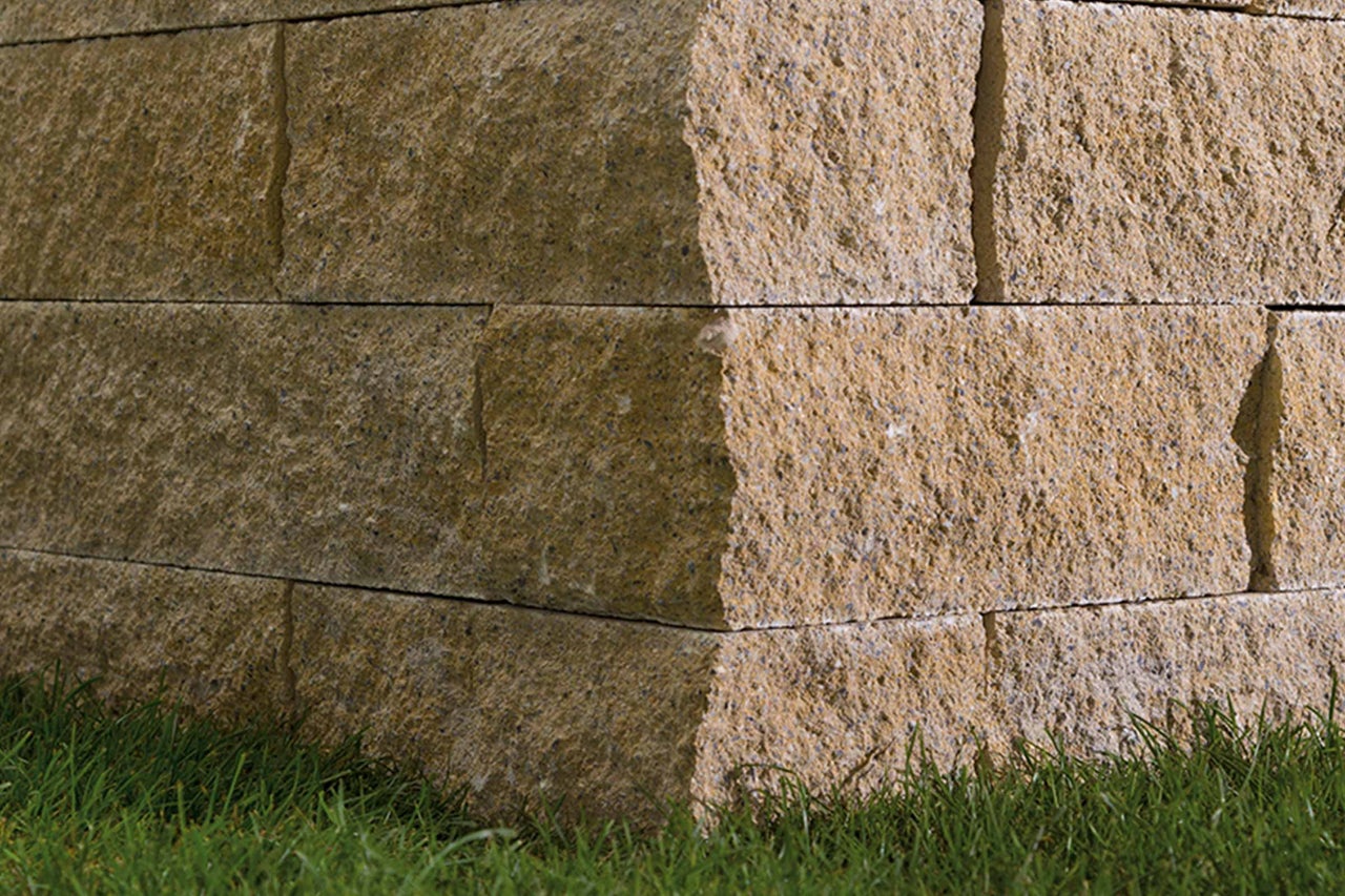 Nahaufnahme einer Trockenmauer aus Stein mit Grasbewuchs