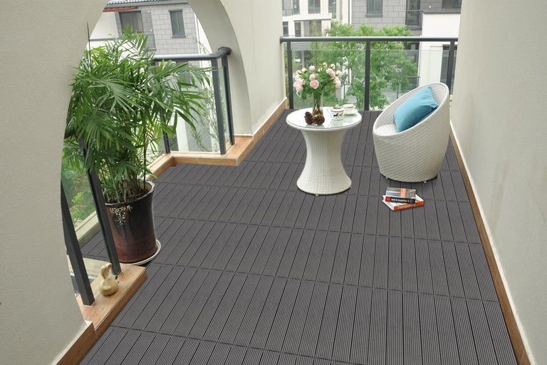 Balkon mit grauen Terrassendielen, Tisch, Stuhl und Topfpflanze.