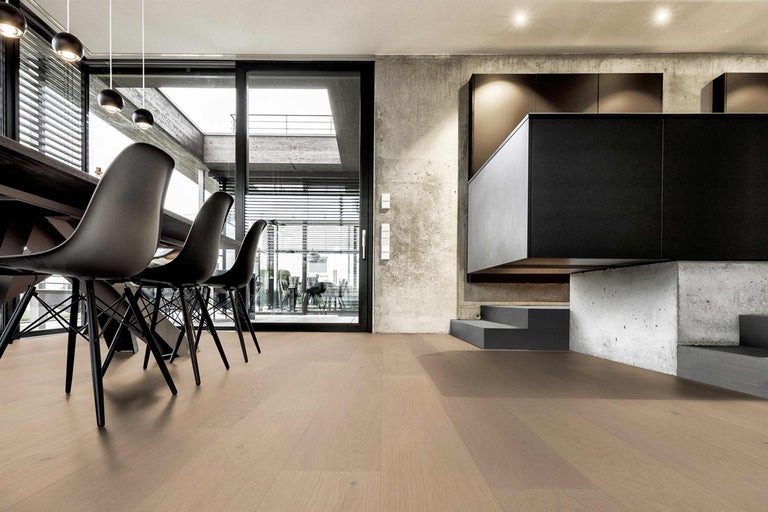 Heller Holzboden in einem modern eingerichteten Raum mit Esstisch und Küchenbereich.