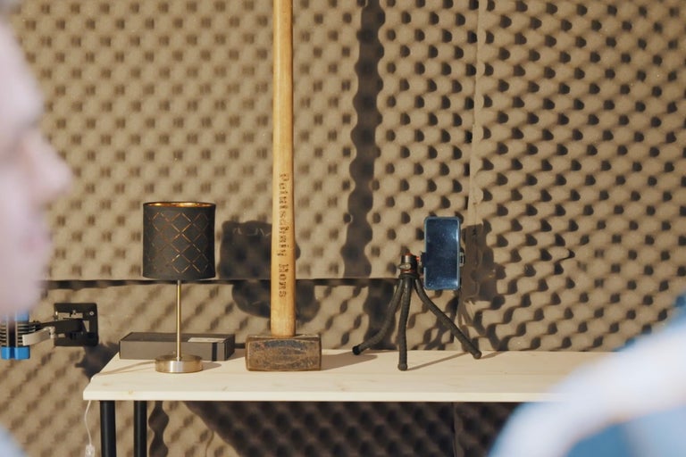 Szene mit einem Hammer, einer Lampe und einem Smartphone auf einem Stativ auf einem Tisch