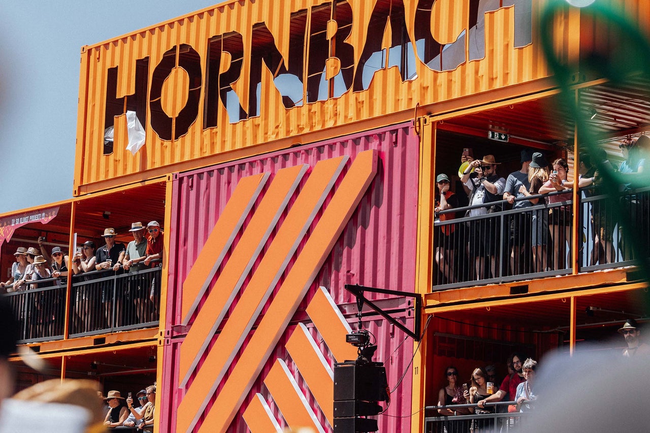 Mehrstöckige Event-Konstruktion aus Schiffscontainern mit Hornbach Logo und Zuschauern auf den Balkonen.