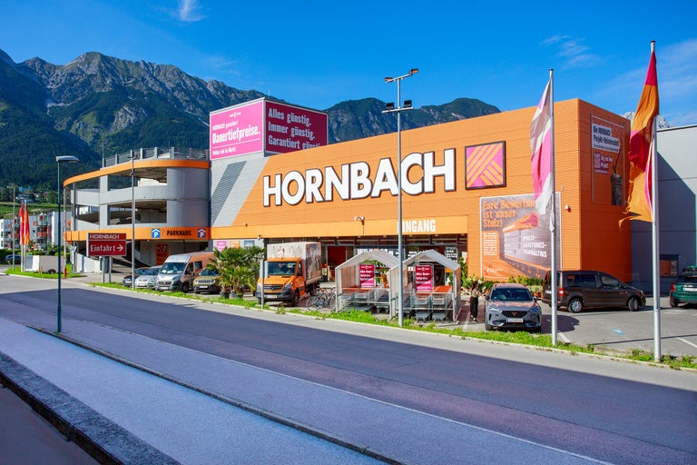 Außenansicht eines Hornbach Baumarktes mit Parkplatz und Bergpanorama