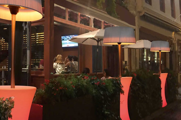 Restaurantterrasse mit beleuchteten Stehlampen und Pflanzenkübeln