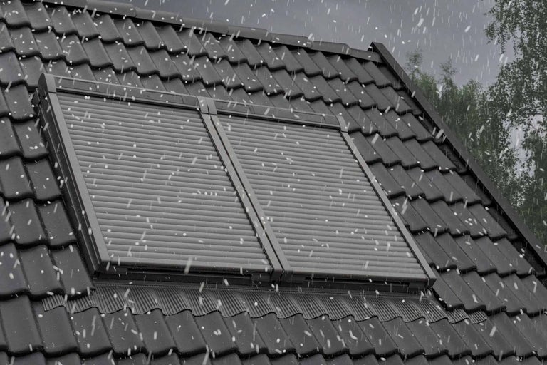 Zwei Dachfensterrollläden auf einem Dach bei Schneefall