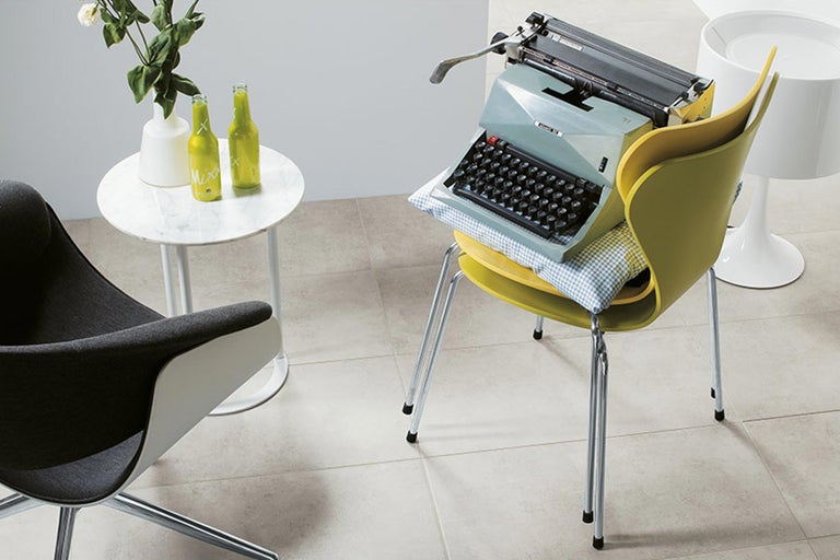 Szene mit Sessel, Beistelltisch, Stehleuchte und Schreibmaschine auf Stuhl