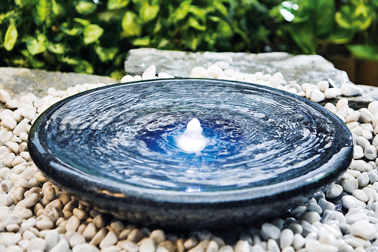 Dekorativer Springbrunnen auf weißen Steinen im Garten