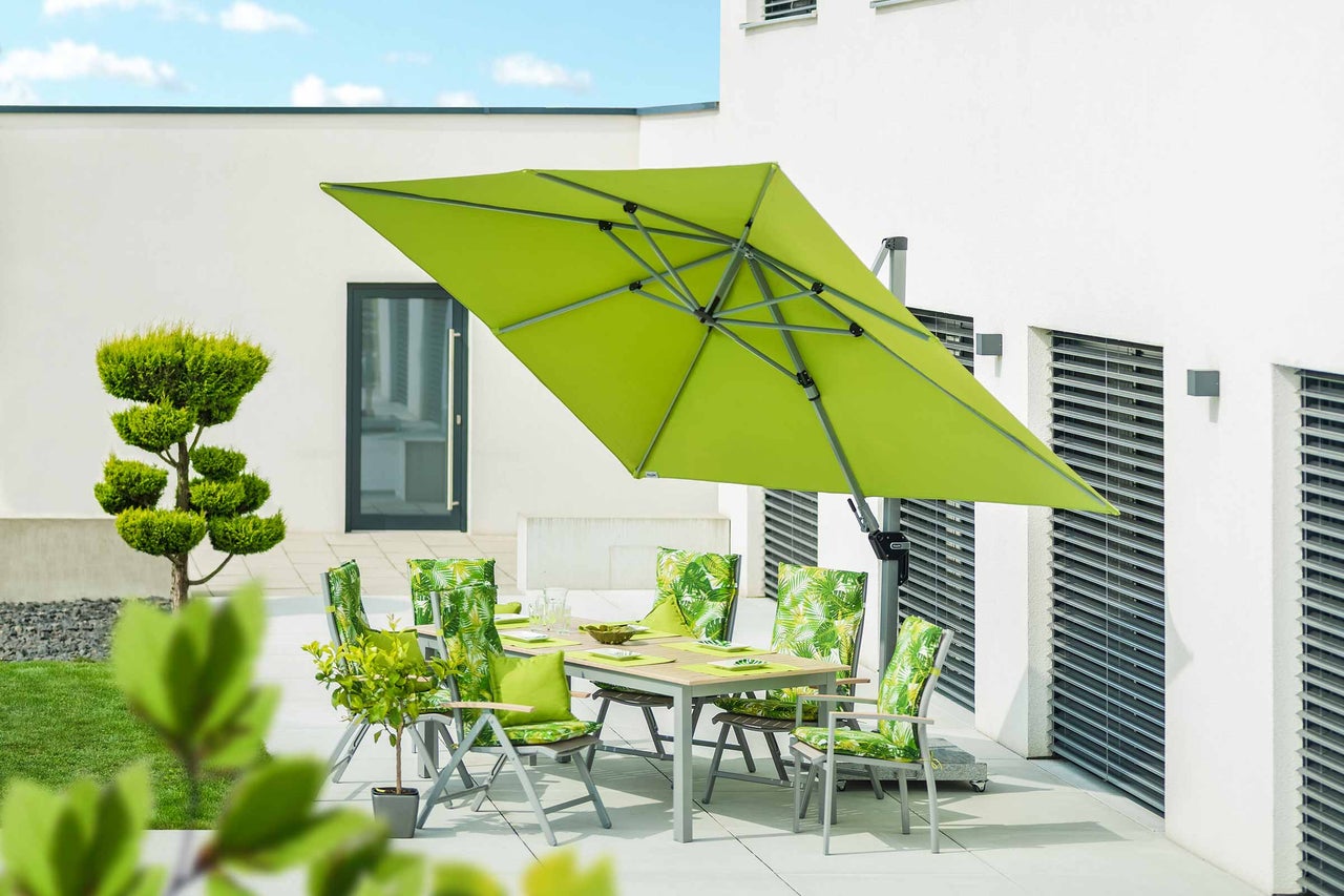Gartenszene mit rechteckigem Sonnenschirm, Gartentisch und Stühlen mit Auflagen