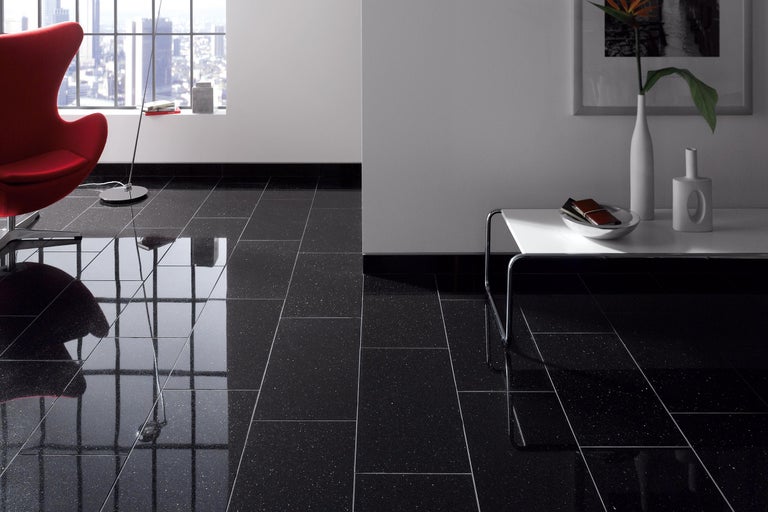 Büro mit Bodenfliesen in dunkler Farbe, Sessel und Tisch