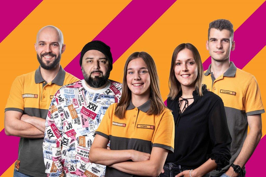 Gruppenfoto von fünf Hornbach Mitarbeitern vor farbigem Hintergrund