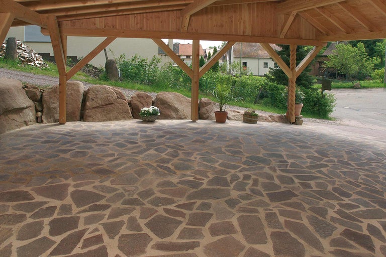 Überdachter Bereich mit Natursteinpflasterung und rustikalen Holzbalken