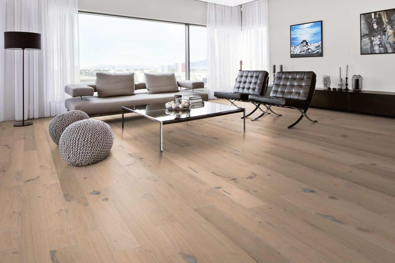 Heller Wohnraum mit Holzboden, Sofa, Sesseln und Fenster