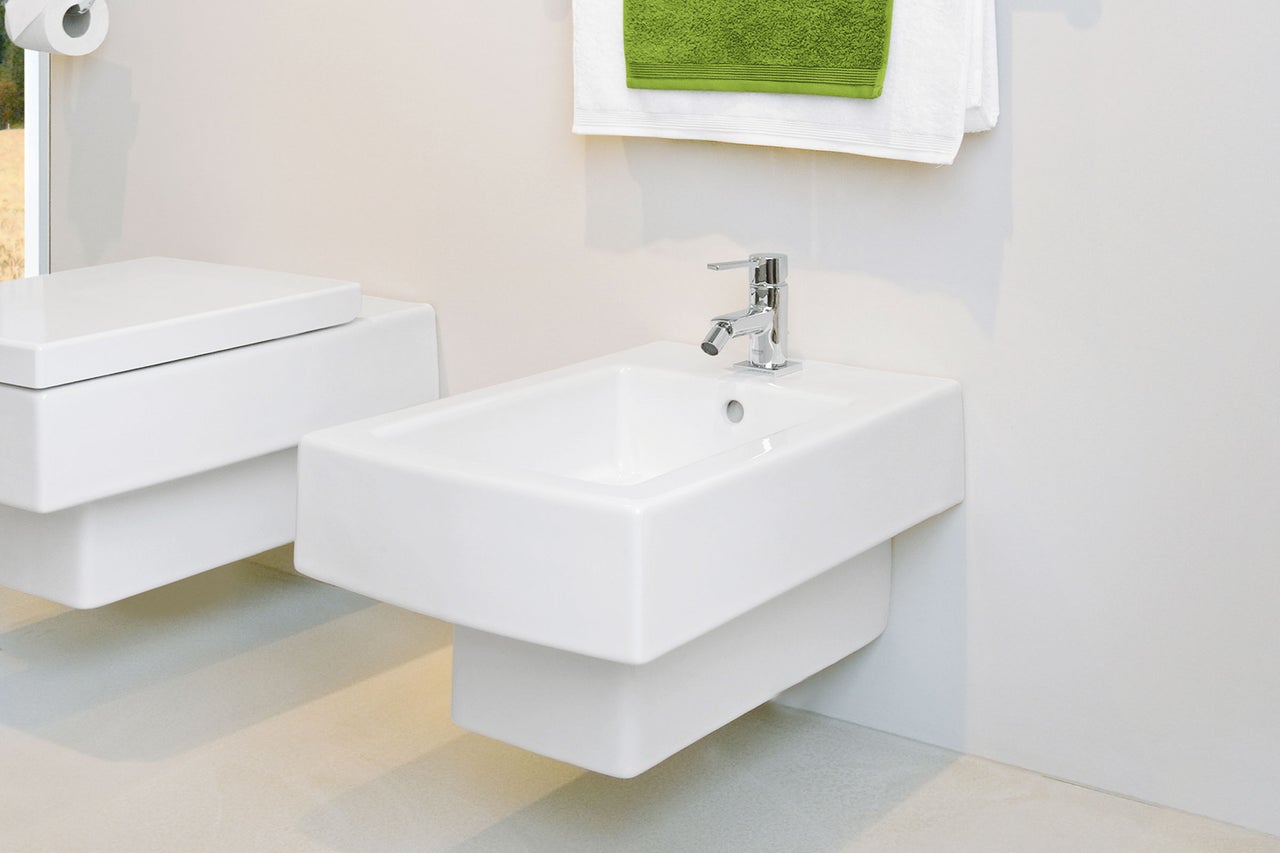Helles Badezimmer mit wandhängendem Bidet und Handtüchern