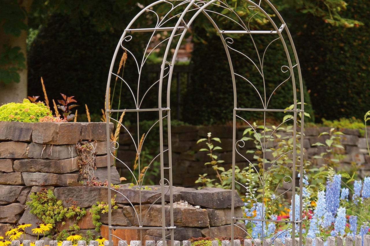 Gartenansicht mit Metallbogen als Rankhilfe für Pflanzen