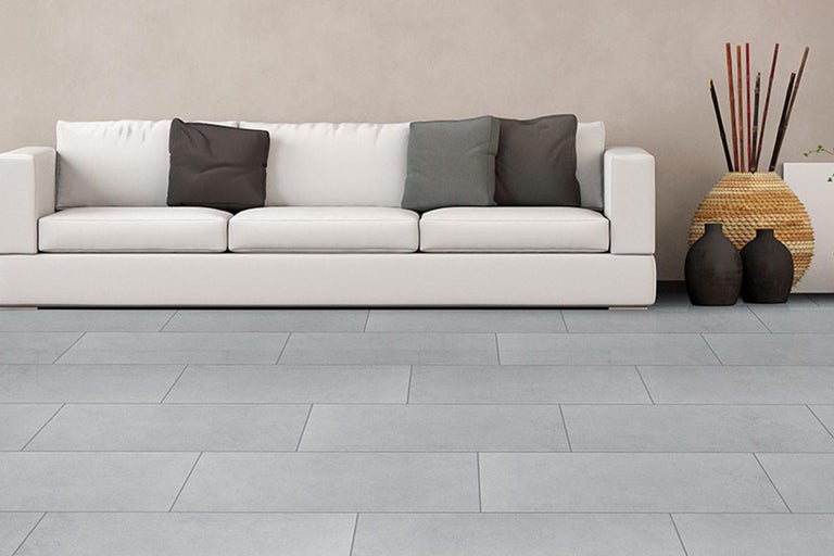 Helles Wohnzimmer mit grauem Fliesenboden, weißem Sofa und dekorativen Elementen